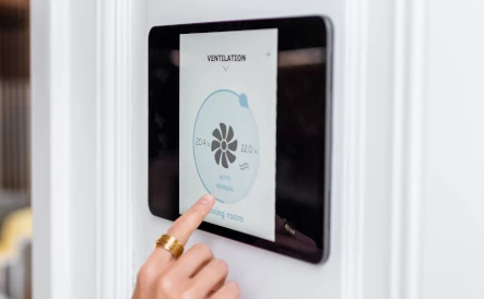 personne qui règle la ventialation de son habitation depuis une tablette