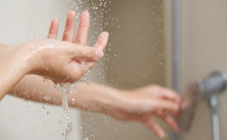 mains qui vérifie la température de l'eau de la douche