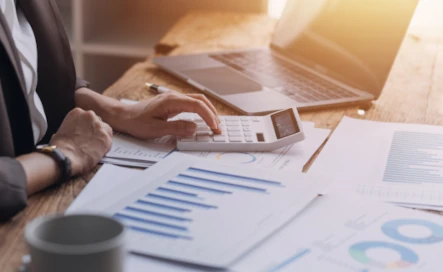 personne qui utilise une calculatrice à coté de son ordinateur et de ses factures d'électricité