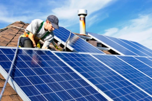 homme portant une casquette sur un toit installant un panneau solaire