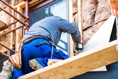 homme en combinaison bleue qui isole une maison par l'extérieur