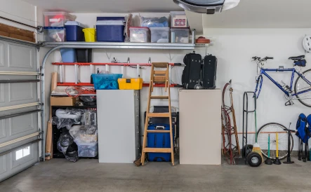 garage d'une maison avec des murs blancs, des outils de bricolage, une échelle en bois et un vélo bleu