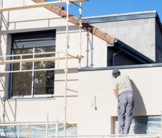 homme qui pose dde l'enduit sur le mur d'une maison