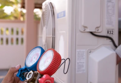 main tenant un appareil de mesure devant une unité extérieure d'une pac air/eau