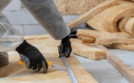 personne portant une combinaison blanche qui pose de la laine de verre