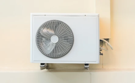 unité extérieure d'une pompe à chaleur blanche sur un mur beige